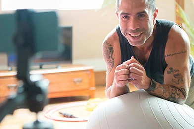 Online personal trainer on a bosu ball recording a session.